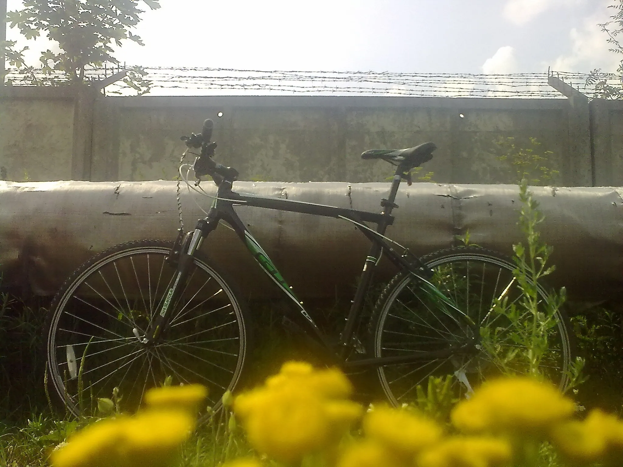 My bicycle near big tubes of central heating and a concrete fence with barbwire