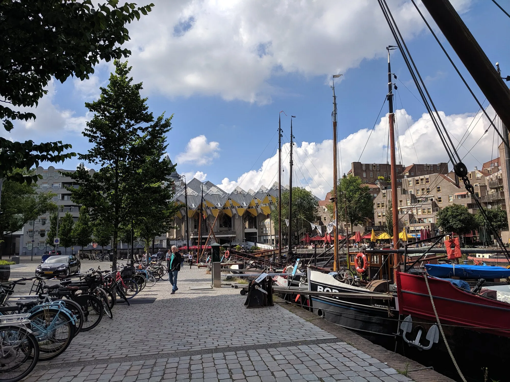 A photo of sailing boats and famous Rotterdam's cube buildings complex on the background